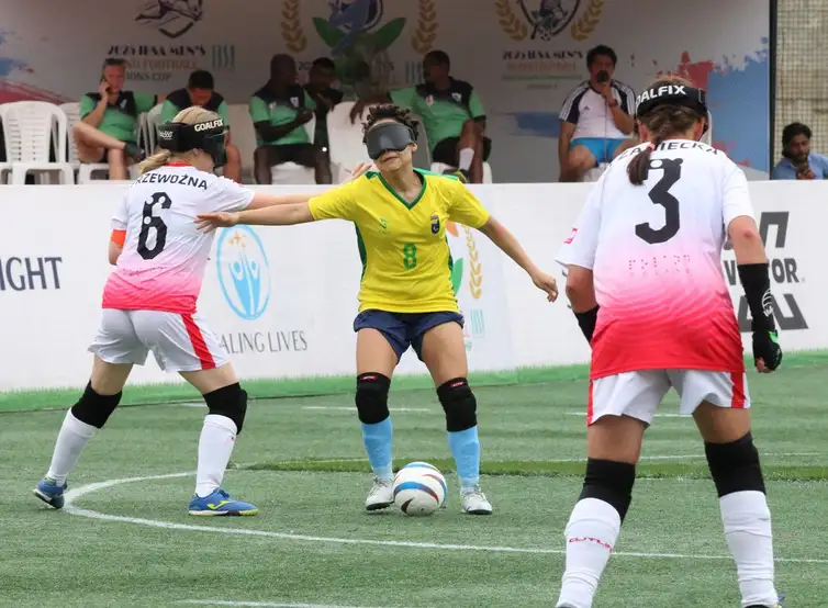 Renan Cacioli/CBDV/Direitos Reservados Copa do Mundo de futebol de cegas - Ao centro, Sarah (camisa 8) é marcada pela zaga da Polônia - Brasil empata em 0 a 0 e avança às semifinais - em 8/10/2025
